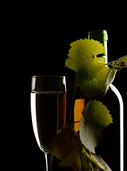 Wijnglas met fles. Stilleven tegen een zwarte achtergrond — Stockfoto