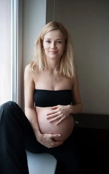 Pencere üzerinde hamile blonde — Stok fotoğraf
