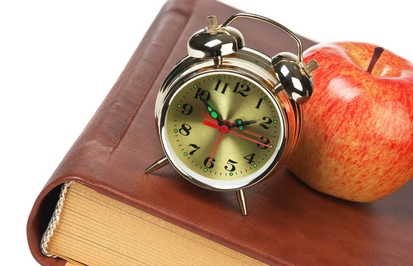 Golden alarm clock and apple on the book isolated