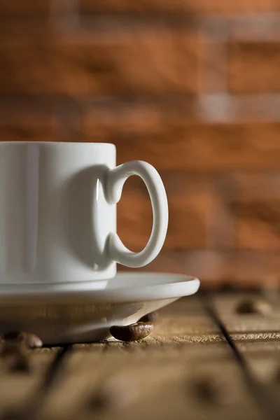Vit kaffekopp på en bakgrund av en tegelvägg — Stockfoto