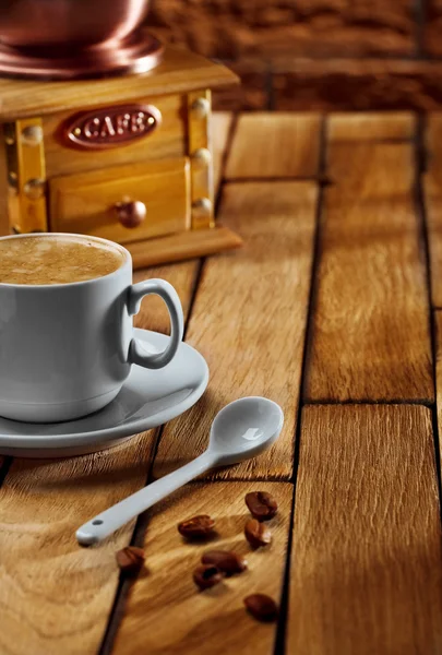 Close-up xícara de café e moedor em mesa de madeira — Fotografia de Stock