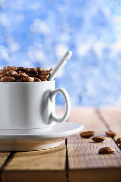 Xícara com grãos de café na mesa de madeira — Fotografia de Stock