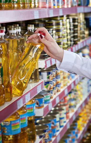 Womens hand selecteert de fles van olie in de winkel — Stockfoto