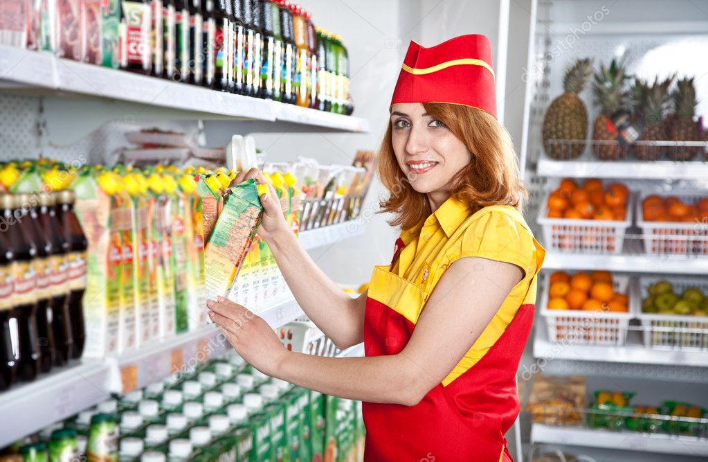 Female the seller in the supermarket holding a box of juice