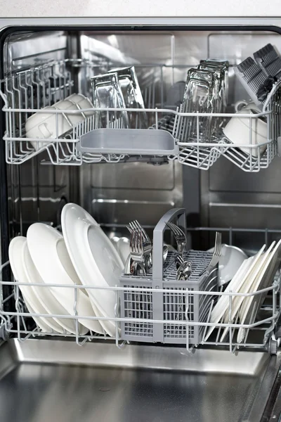 Посудомоечная машина с белыми пластинами и стальными столовыми приборами — стоковое фото