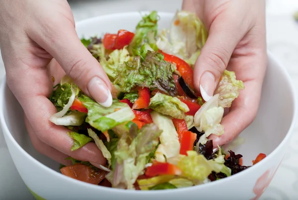 stock image The woman hands mixes salad