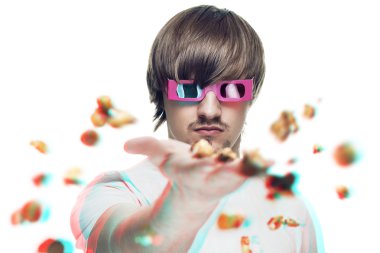 Young man in stereo glasses throwing popcorn at the viewer 3d mo clipart