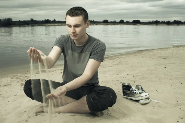 周到的年轻男子坐在沙滩上 — 图库照片