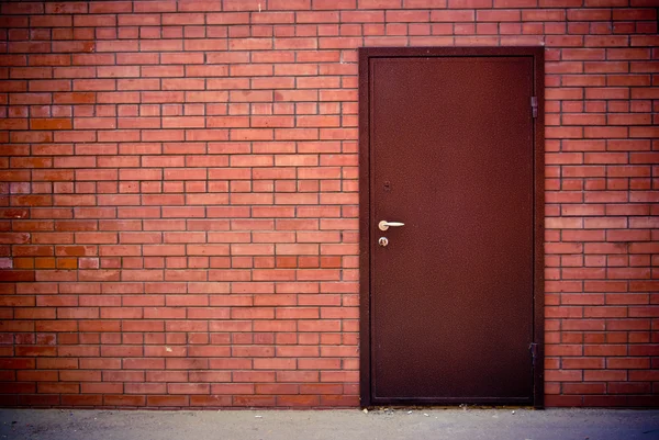 Pared de ladrillo rojo y la puerta cerrada de hierro — Foto de Stock