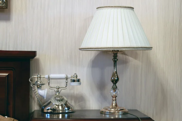Стол и прикроватная лампа с телефоном в интерьере — стоковое фото