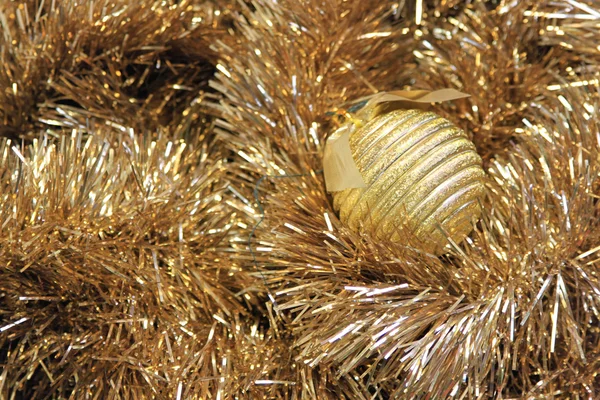 Bola de Natal dourada em um ouropel dourado — Fotografia de Stock