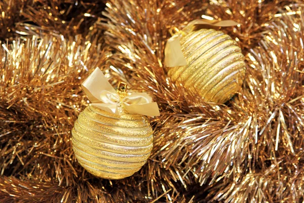 Bolas de Natal douradas em um ouropel dourado — Fotografia de Stock