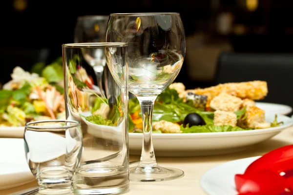 Γυαλιά και τα πιάτα στο τραπέζι σε εστιατόριο - υπόβαθρο των τροφίμων — Φωτογραφία Αρχείου
