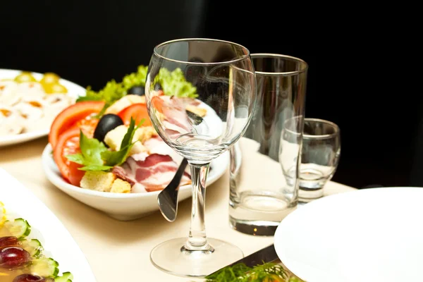Γυαλιά και τα πιάτα στο τραπέζι σε εστιατόριο - υπόβαθρο των τροφίμων — Φωτογραφία Αρχείου