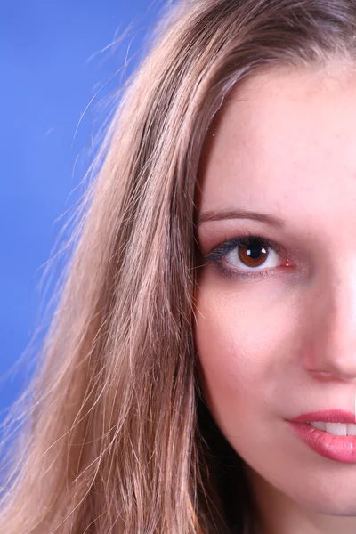 Rosto da jovem mulher no fundo azul — Fotografia de Stock