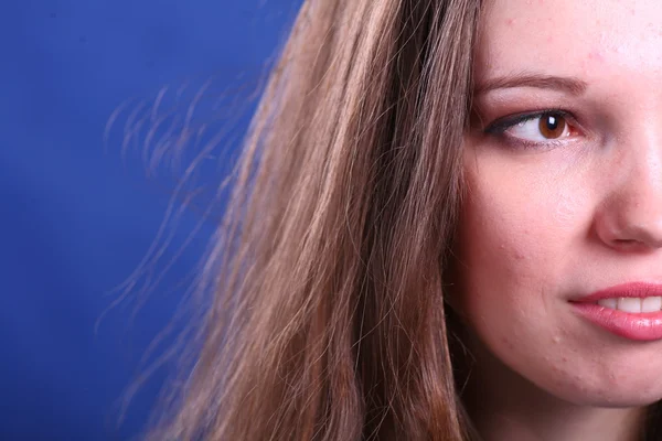 蓝色背景上的年轻女人的脸 — 图库照片