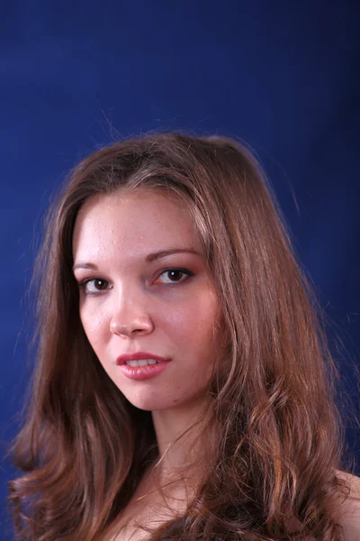 Face of young woman on blue background — Stock Photo, Image