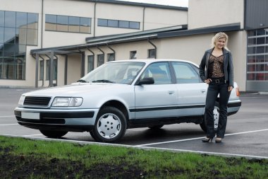 Blonde girl with a car at empty parking place. clipart