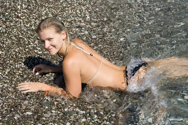 Blondie girl na oblázkové pláži. — Stock fotografie