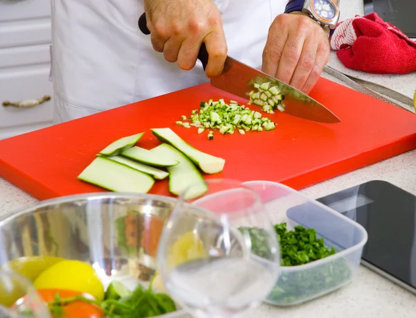 Chef cortando a abobrinha em uma placa — Fotografia de Stock