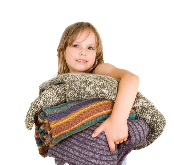 Kleines Mädchen mit einem Stapel Pullover — Stockfoto