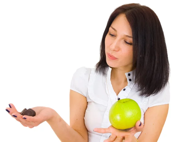 Young woman comparing apple with chocolates — Stock Photo, Image