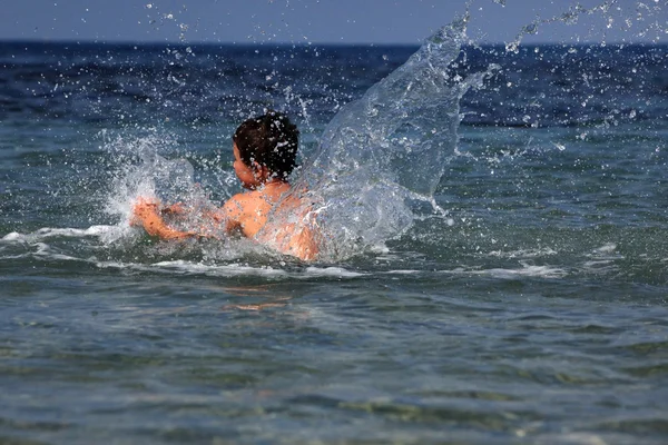 Мальчик в море с брызгами — стоковое фото