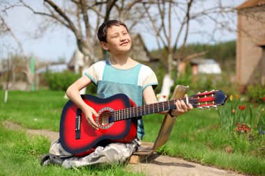 Music student playing the guitar outdoors clipart