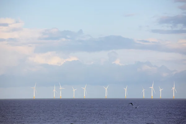 stock image Wind power station - wind turbine in the sea against blue sky