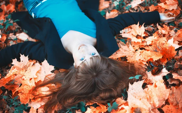 Meisje liggen in de herfst bladeren — Stockfoto