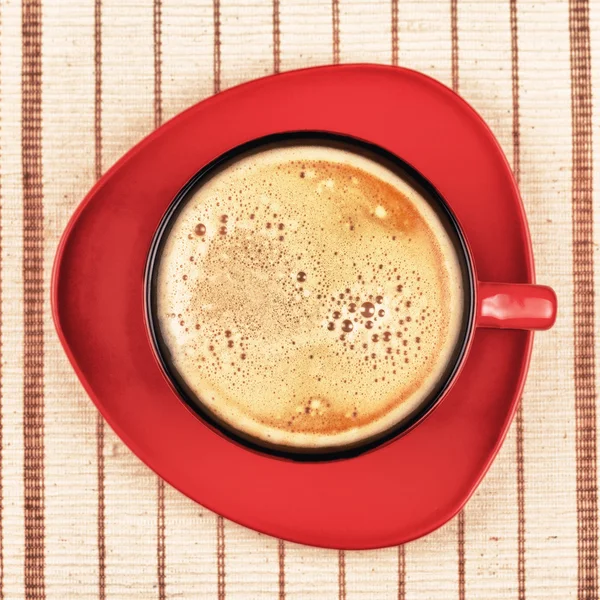 Copo de café vermelho na toalha de mesa listrada — Fotografia de Stock