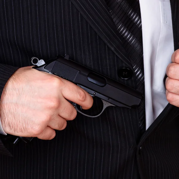 Homem tirando sua arma do bolso do casaco — Fotografia de Stock