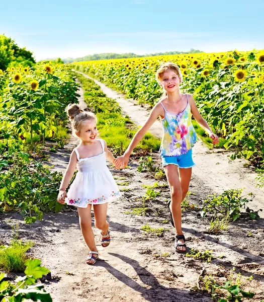 Kinderen lopen over zonnebloem veld buiten. — Stockfoto