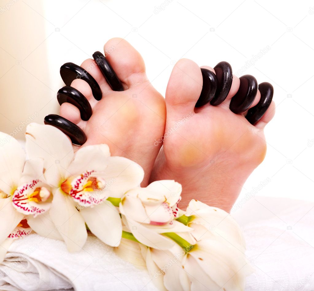 Woman receiving stone massage on feet.