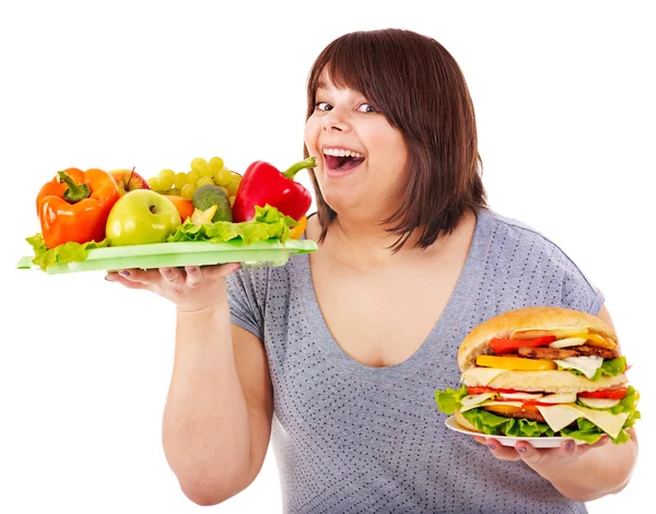 Kadın meyve ve hamburger arasında seçim yapma. — Stok fotoğraf