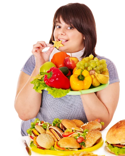 Mulher escolhendo entre frutas e hambúrguer . — Fotografia de Stock