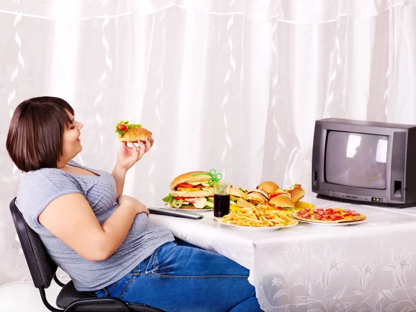 Kvinna äta snabbmat och tittar på tv. — Stockfoto