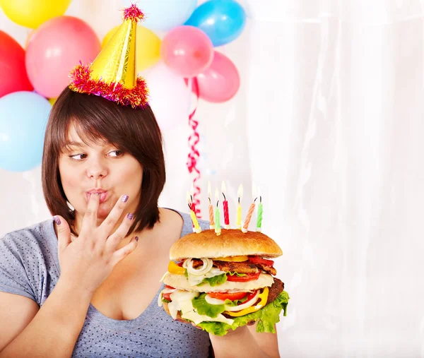 Woman eating hamburger at birthday. — Stock Photo, Image