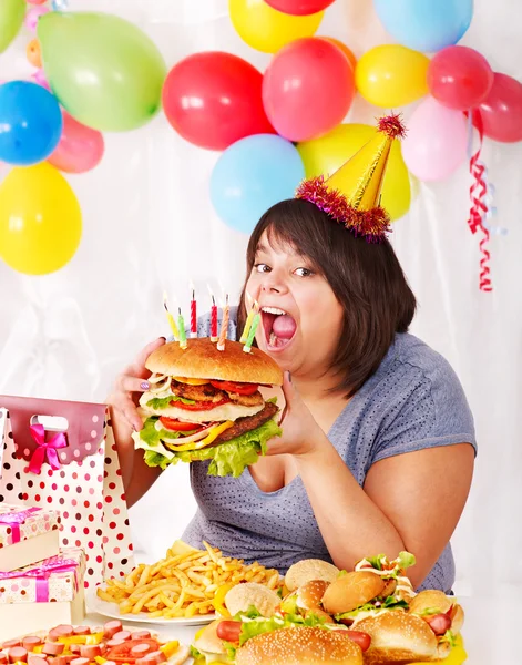 Woman eating hamburger at birthday. Royalty Free Stock Images