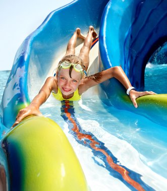 Child on water slide at aquapark. clipart