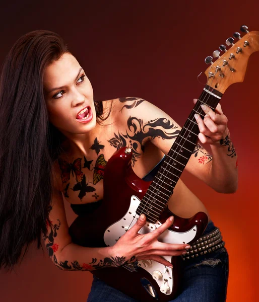 Aggressive girl with tattoo playing guitar. — Stock Photo, Image