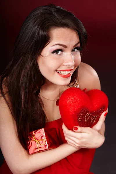 Menina com coração e caixa de presente no fundo vermelho . — Fotografia de Stock