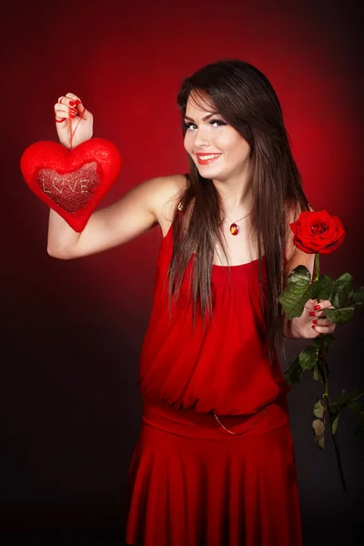 Holka se srdcem a květ růže na červeném pozadí. — Stock fotografie