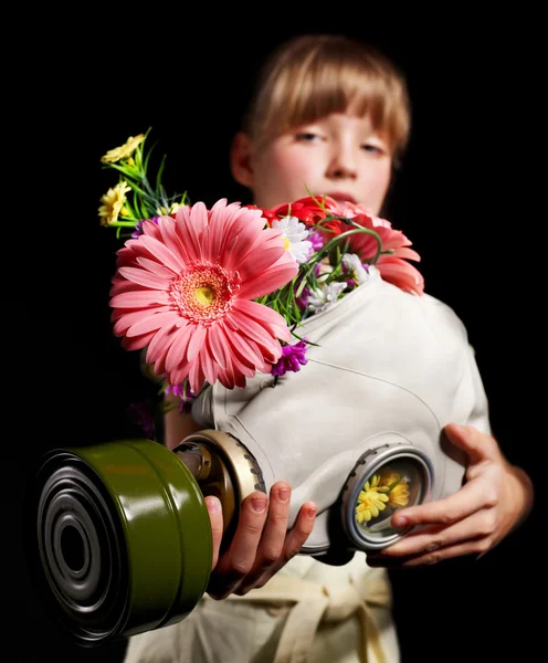 Niño sosteniendo flores y máscara de gas  . — Foto de Stock