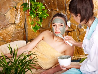 Young woman having clay body mask. clipart