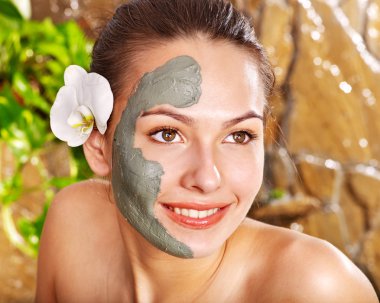 Young woman having clay facial mask. clipart