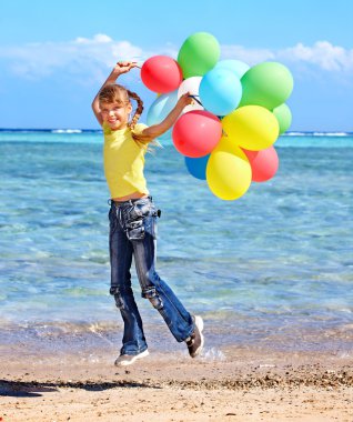 Balonlar ile plajda oynayan çocuk