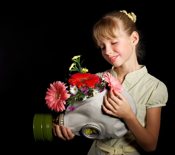 Dítě drží květiny a plynovou masku . — Stock fotografie