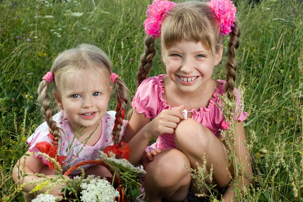 Två liten flicka i grönt gräs. — Stockfoto