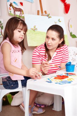 Child playing with teacher in preschool. clipart